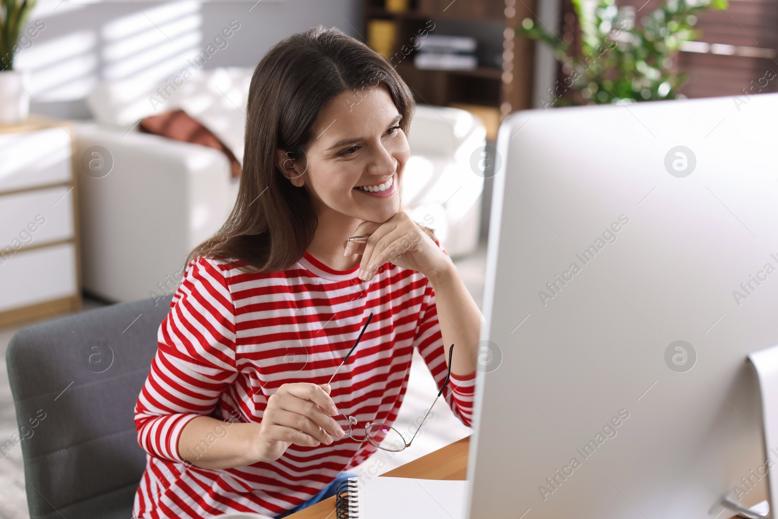 Photo of Happy woman working with computer at desk indoors. Home office