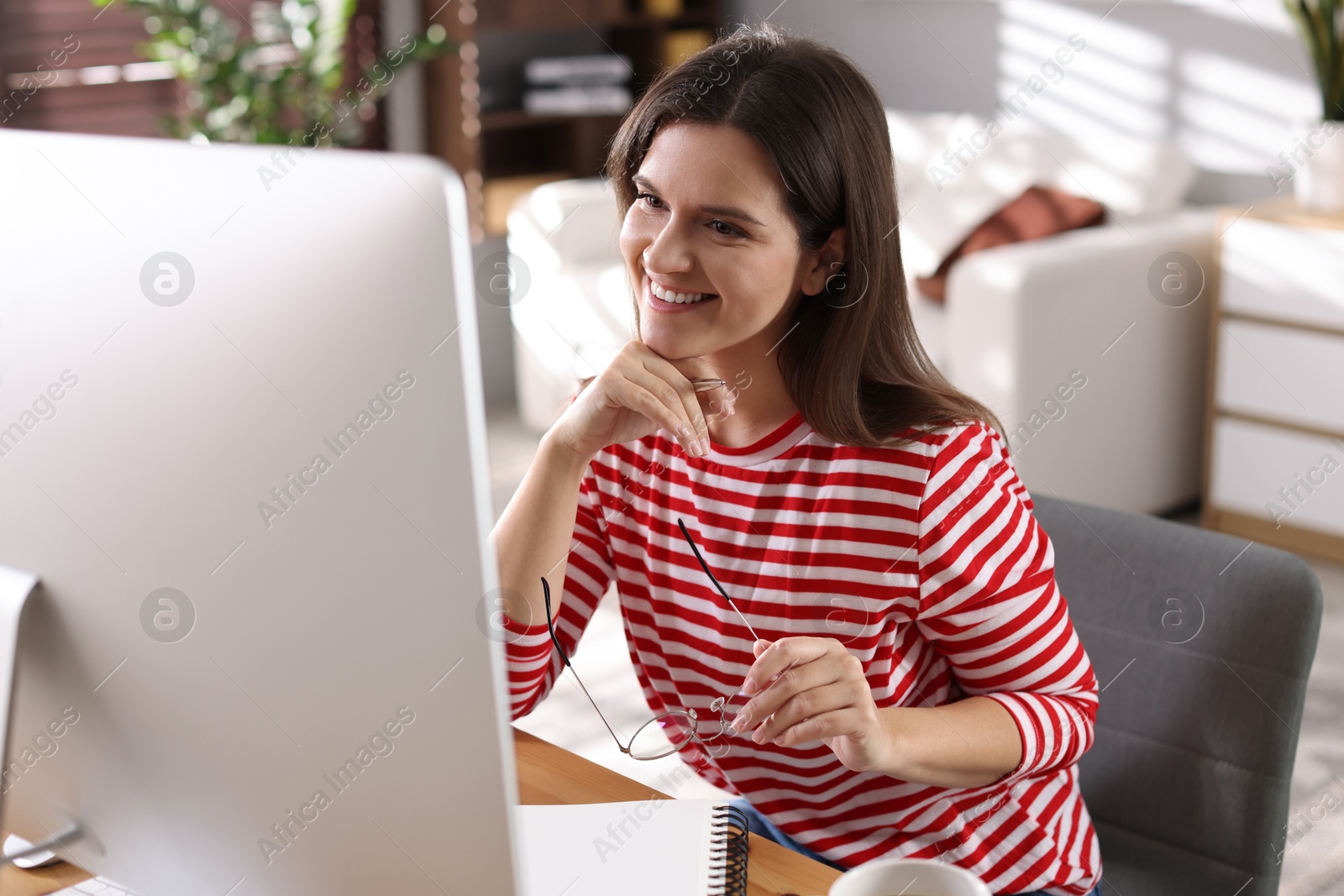 Photo of Happy woman working with computer at desk indoors. Home office