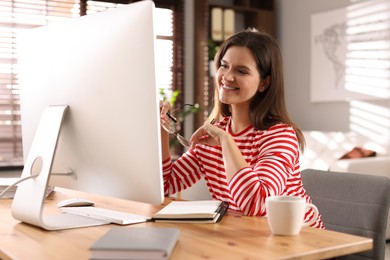 Photo of Happy woman working with computer at desk indoors. Home office