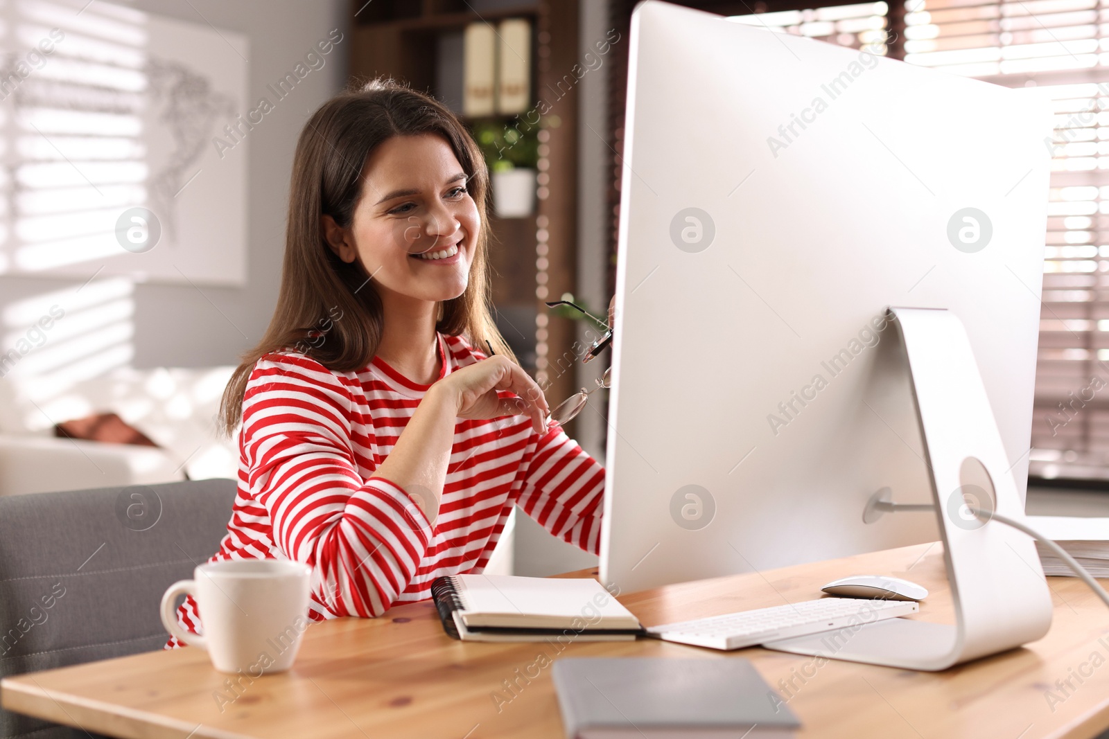 Photo of Happy woman working with computer at desk indoors. Home office