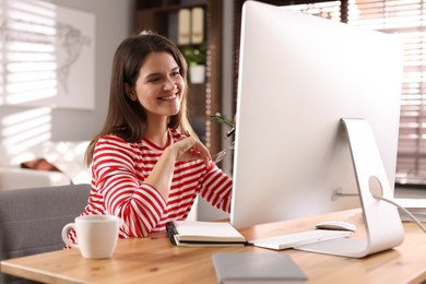 Photo of Happy woman working with computer at desk indoors. Home office