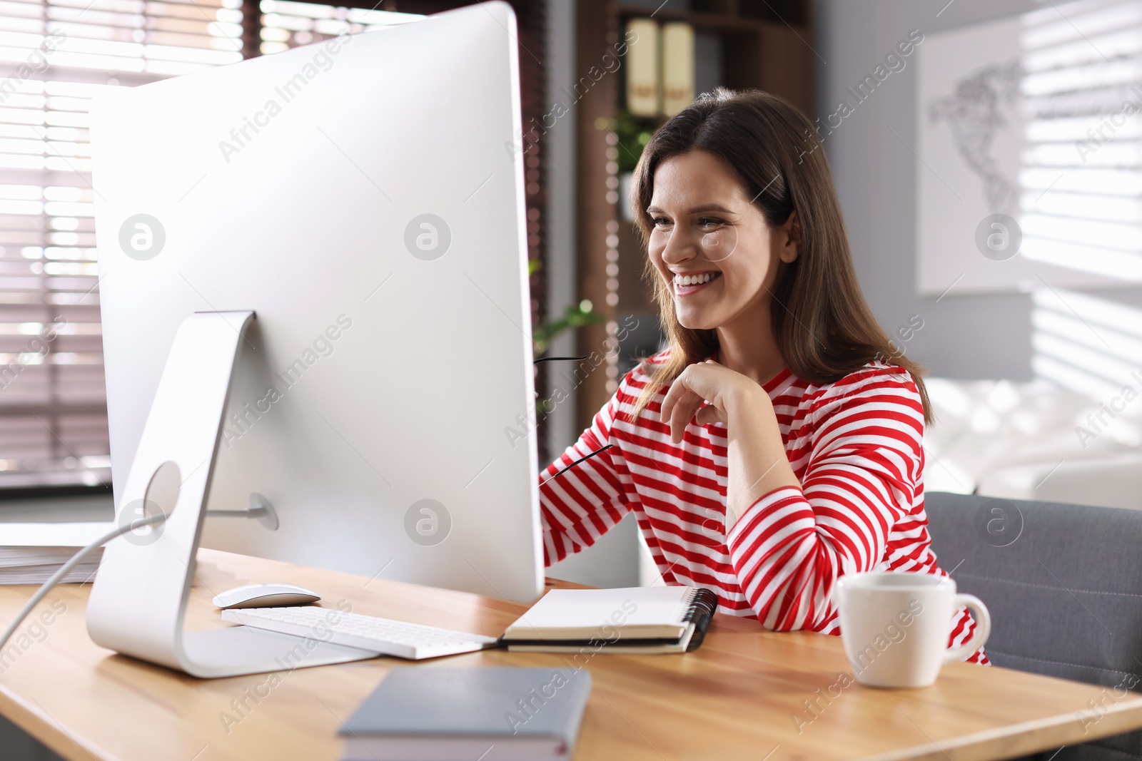 Photo of Happy woman working with computer at desk indoors. Home office