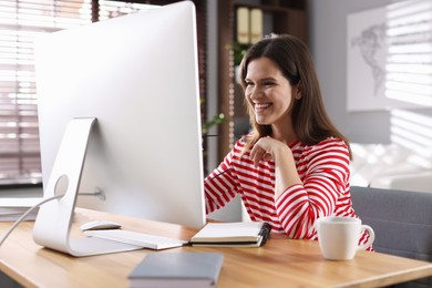 Photo of Happy woman working with computer at desk indoors. Home office