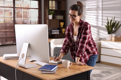 Photo of Happy woman working with computer at desk indoors. Home office