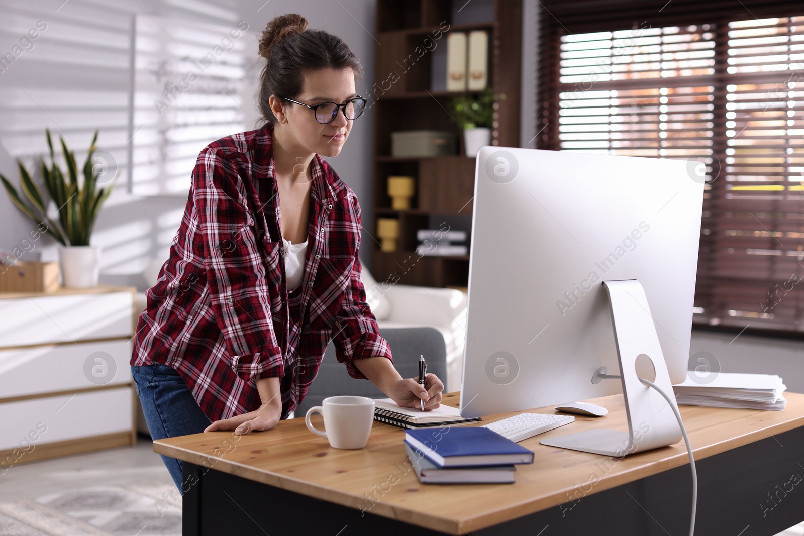 Photo of Beautiful woman working with computer at desk indoors. Home office