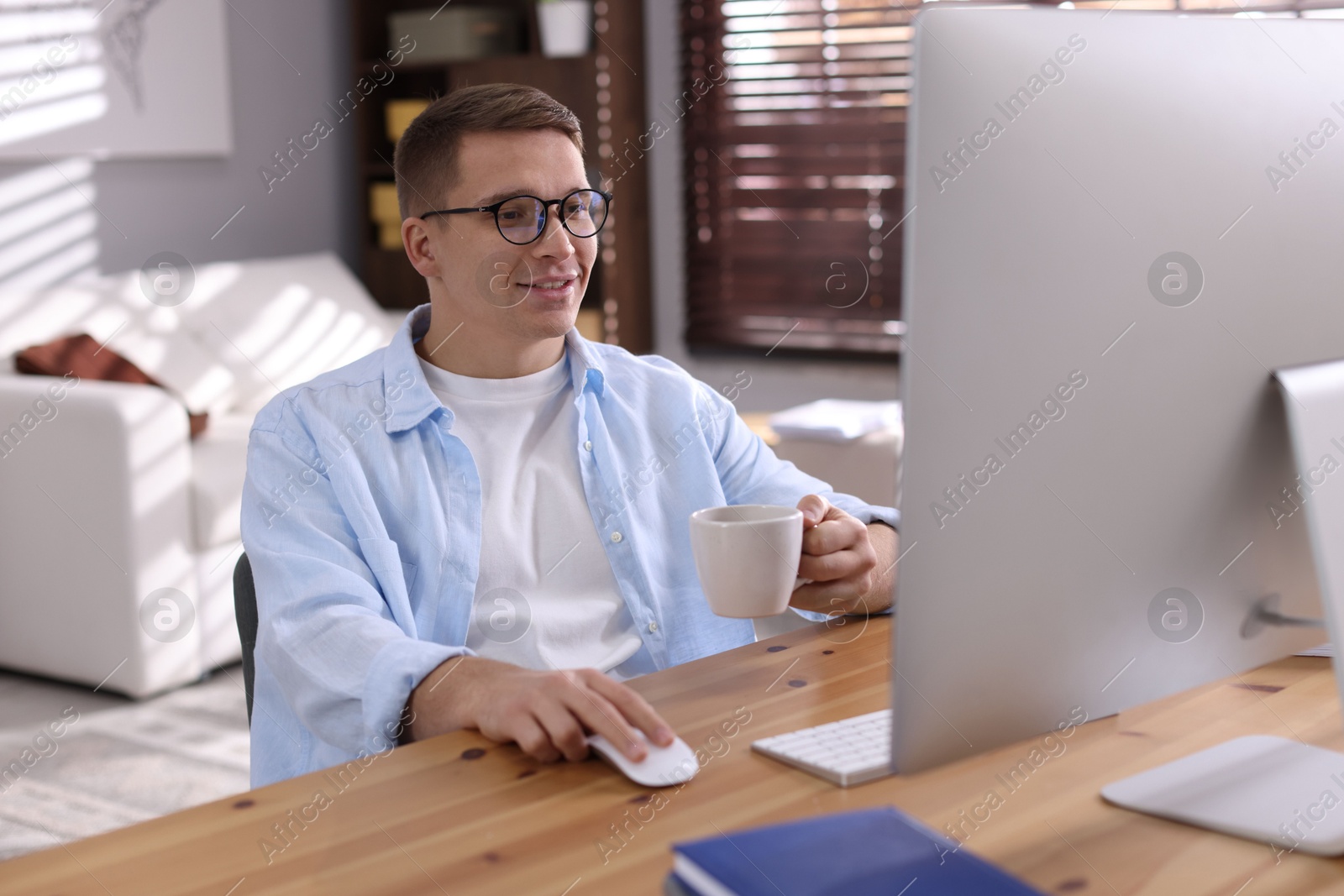 Photo of Happy man working with computer at desk indoors. Home office