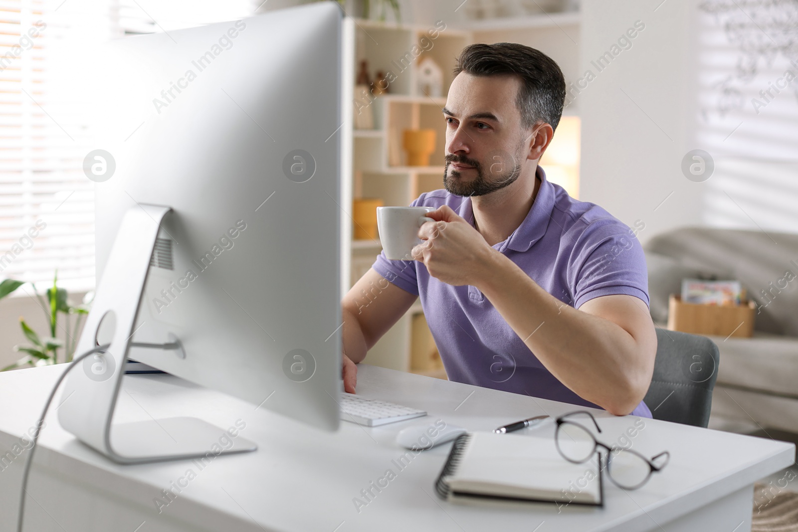 Photo of Handsome man working with computer at desk indoors. Home office