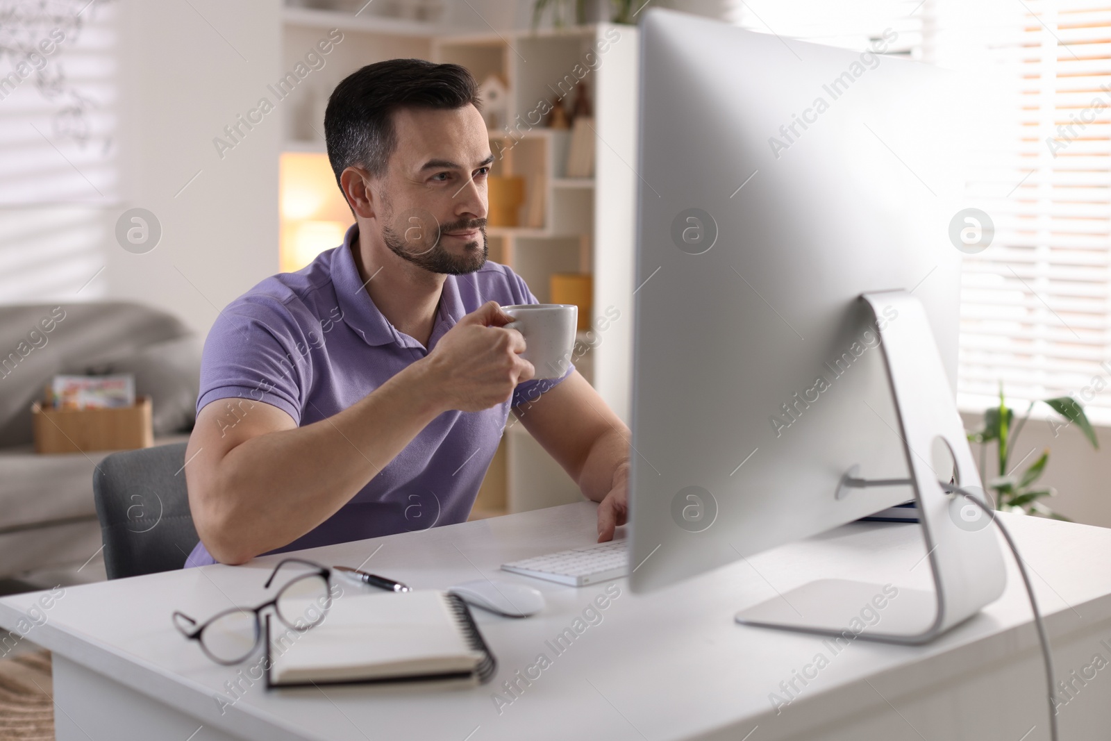 Photo of Handsome man working with computer at desk indoors. Home office