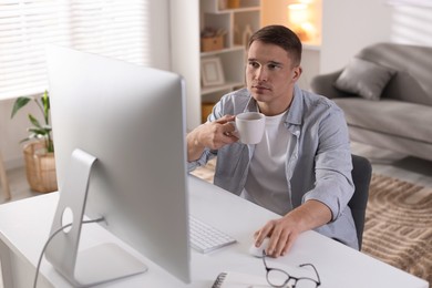 Photo of Handsome man working with computer at desk indoors. Home office