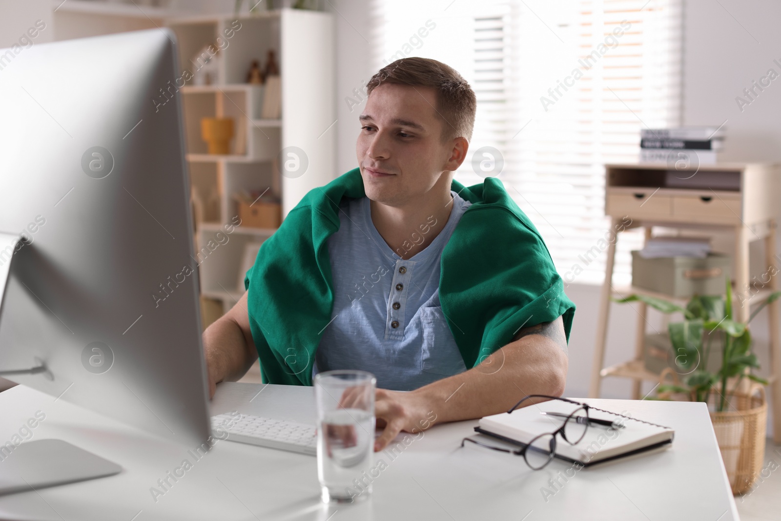 Photo of Handsome man working with computer at desk indoors. Home office