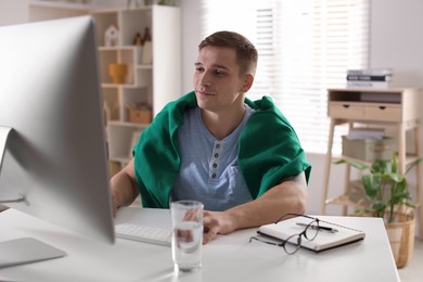 Handsome man working with computer at desk indoors. Home office