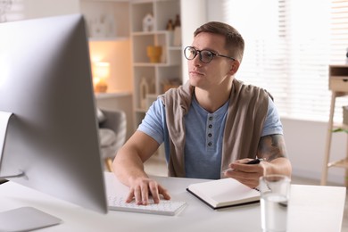 Handsome man working with computer at desk indoors. Home office