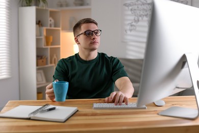 Photo of Handsome man working with computer at desk indoors. Home office