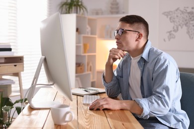 Handsome man working with computer at desk indoors. Home office