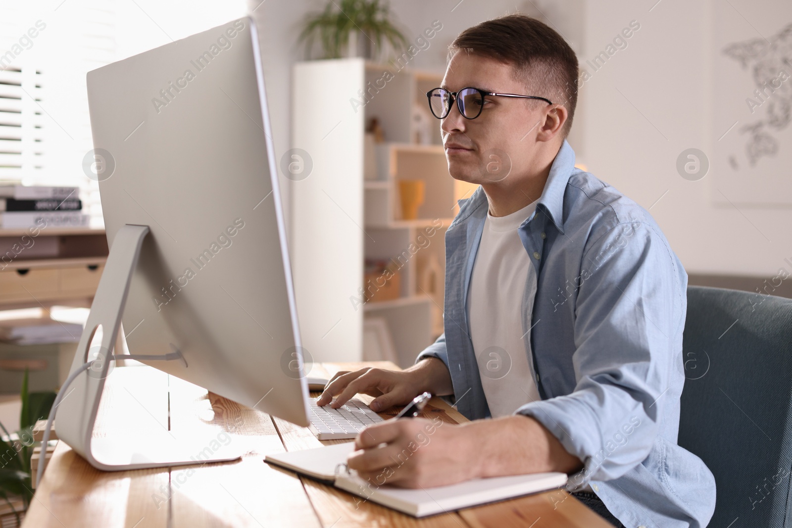 Photo of Handsome man working with computer at desk indoors. Home office