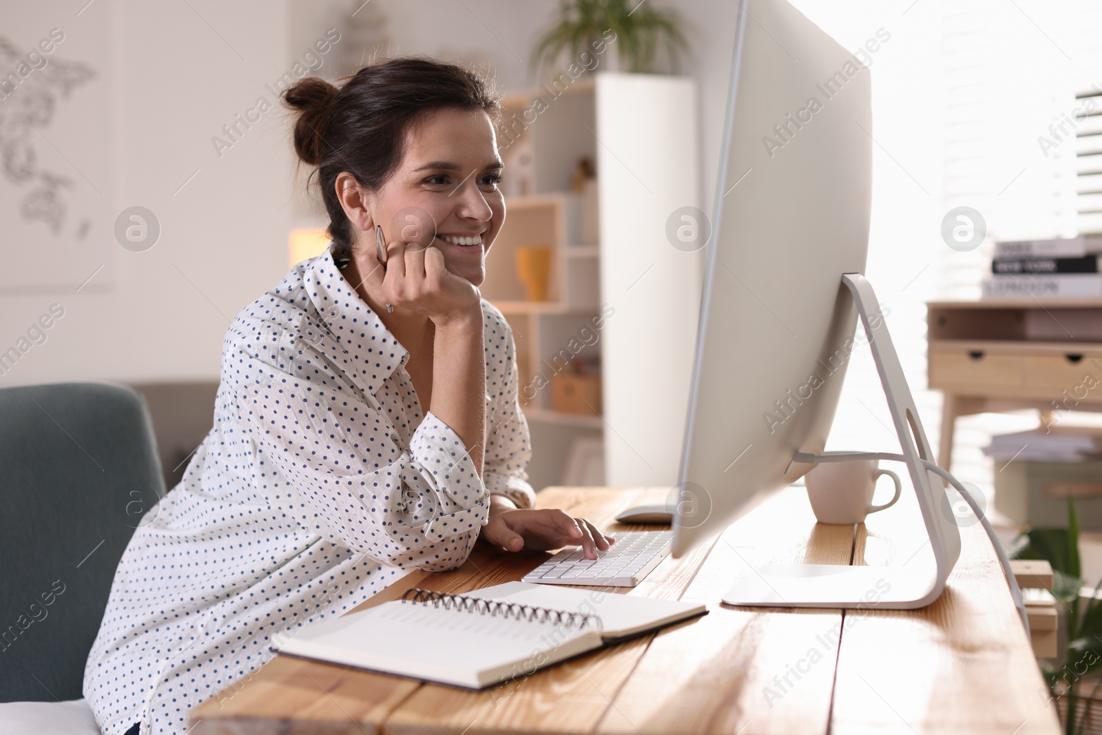 Photo of Happy woman working with computer at desk indoors. Home office