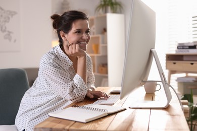 Happy woman working with computer at desk indoors. Home office