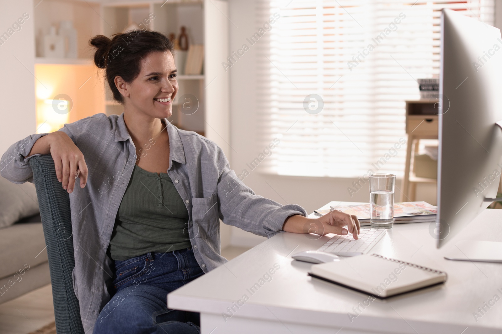 Photo of Happy woman working with computer at desk indoors. Home office