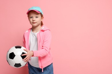 Photo of Little girl with soccer ball on pink background, space for text