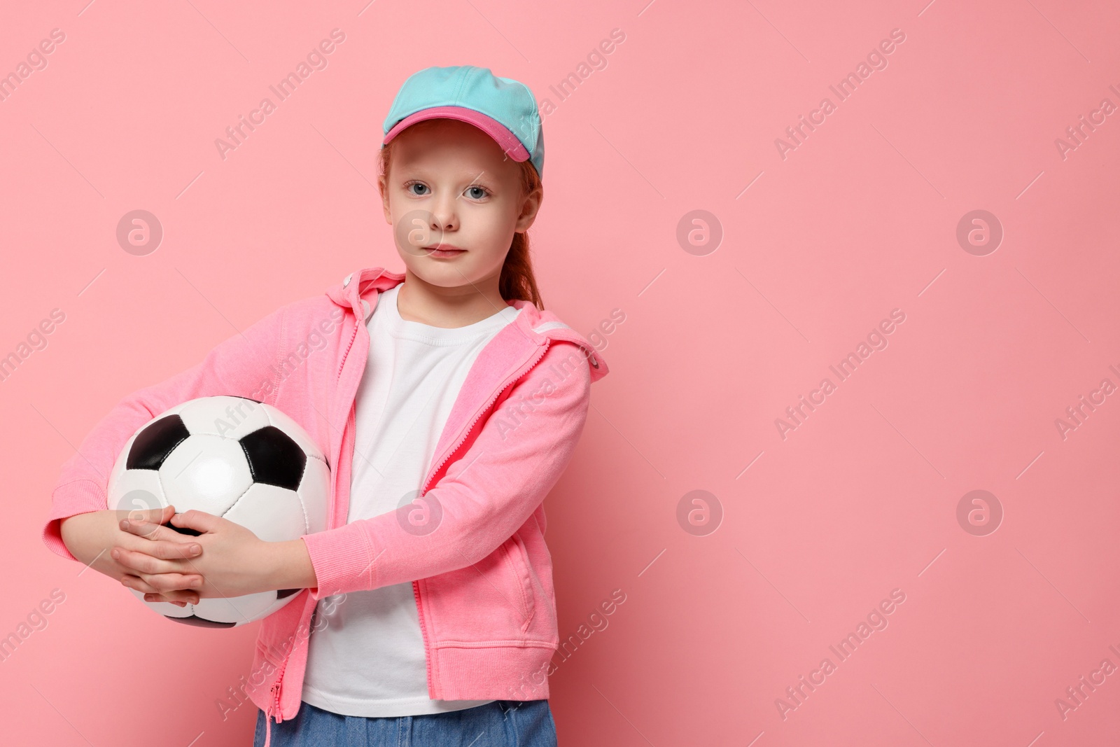 Photo of Little girl with soccer ball on pink background, space for text