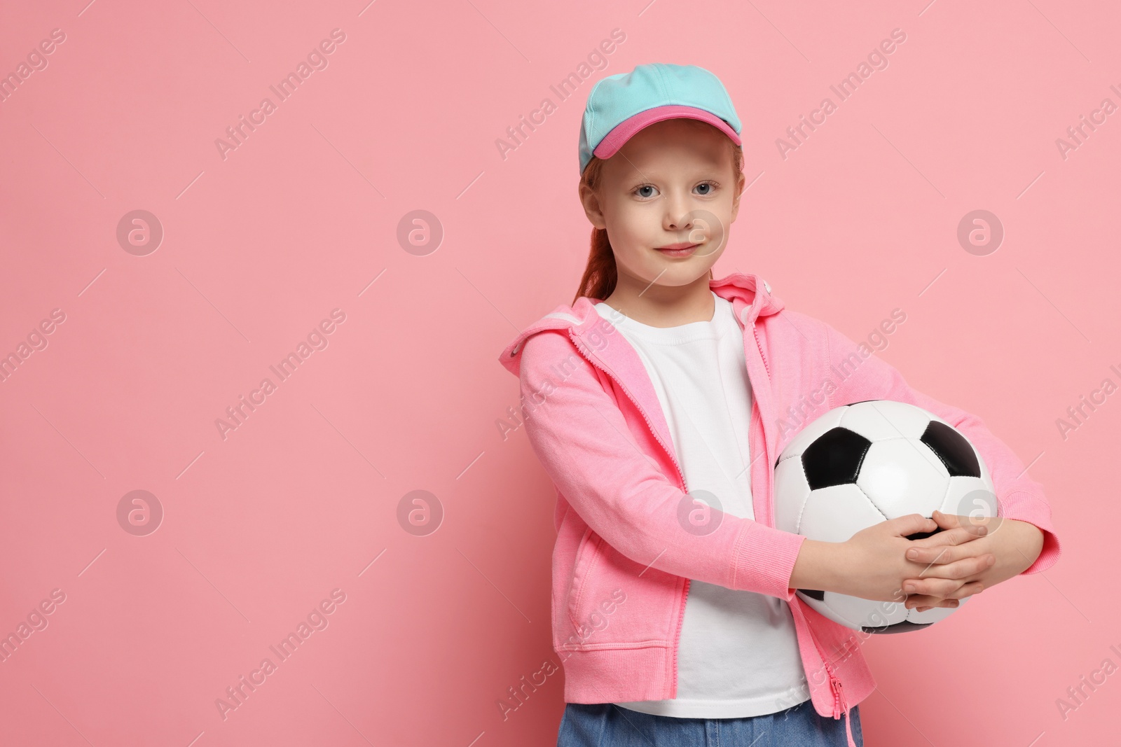 Photo of Little girl with soccer ball on pink background, space for text