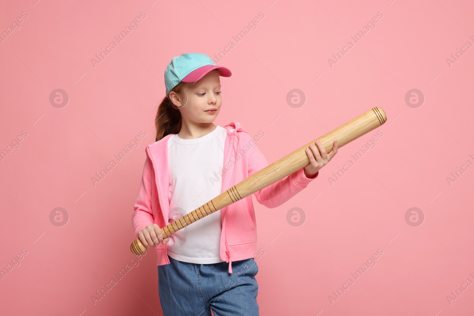 Photo of Little girl with baseball bat on pink background