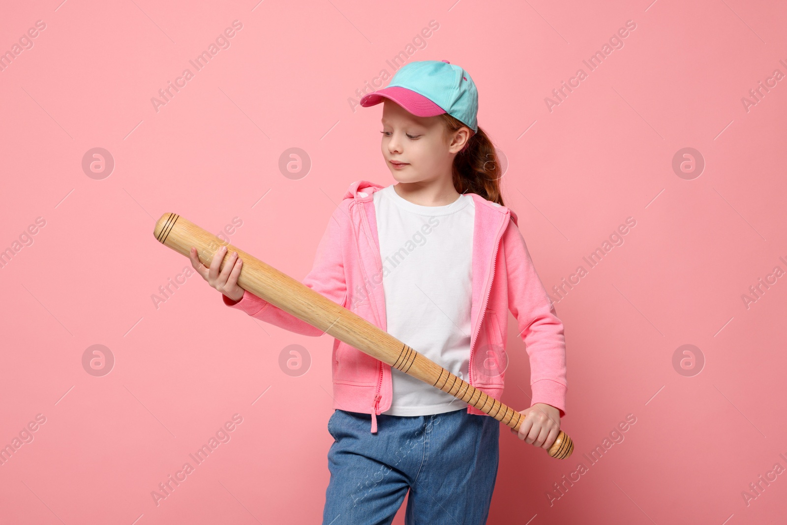 Photo of Little girl with baseball bat on pink background