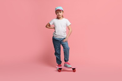 Little girl with penny board on pink background