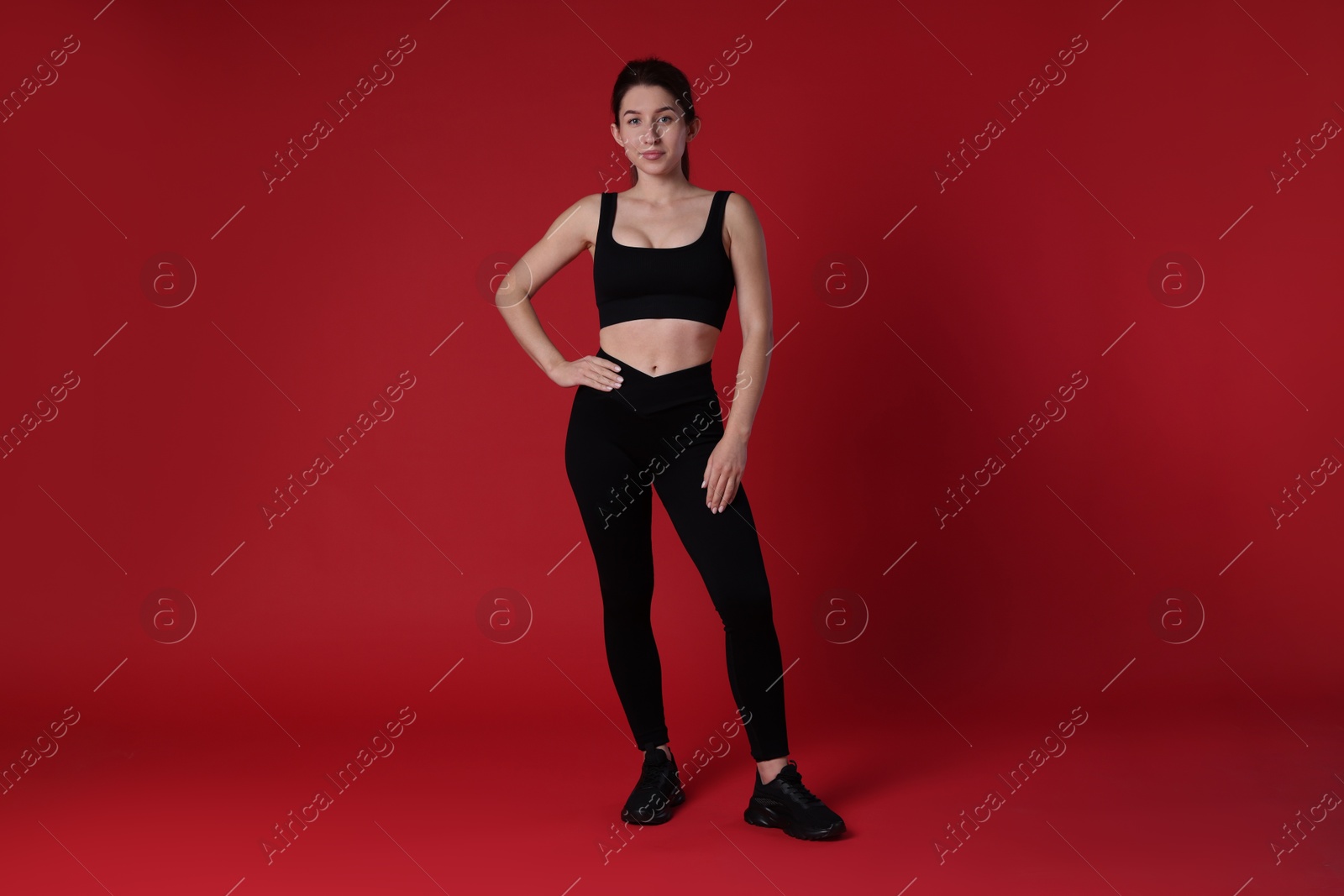 Photo of Portrait of woman in sportswear on red background