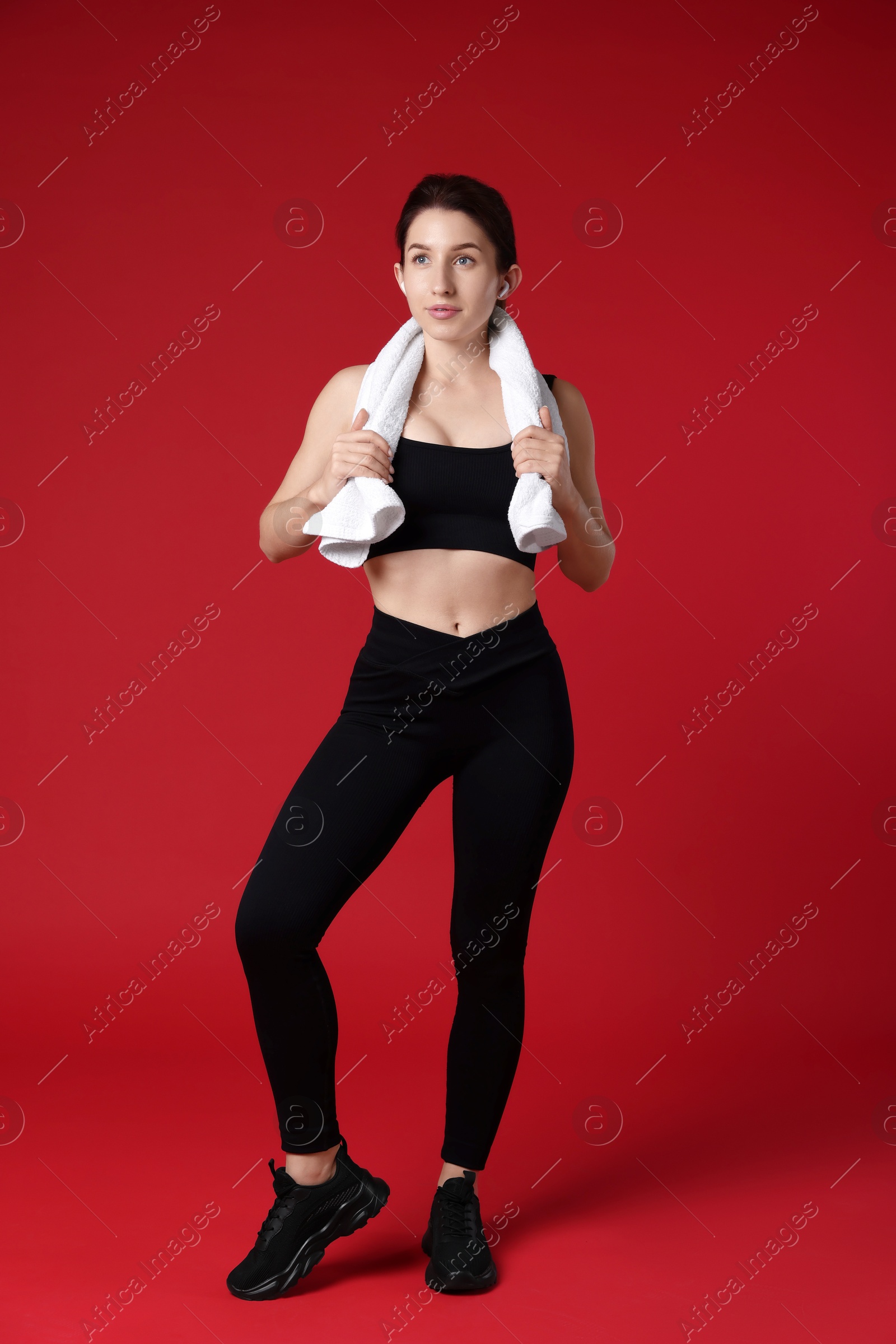 Photo of Woman in sportswear with towel on red background