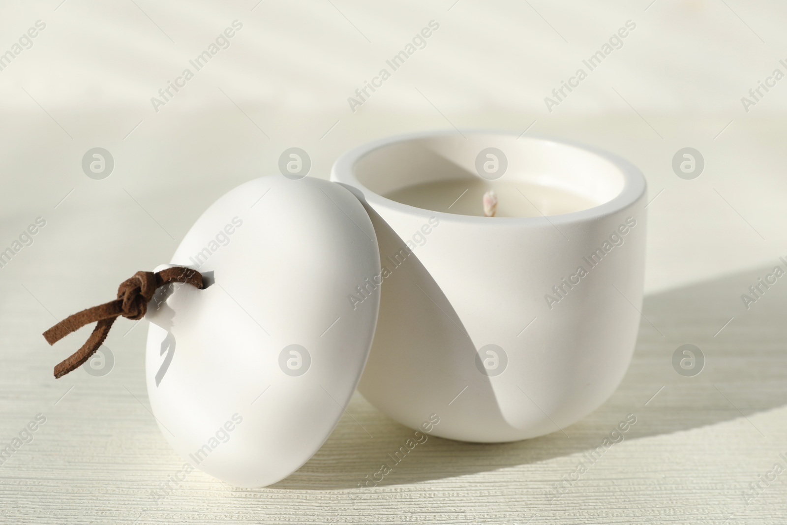 Photo of Soy candle and lid on white wooden table, closeup