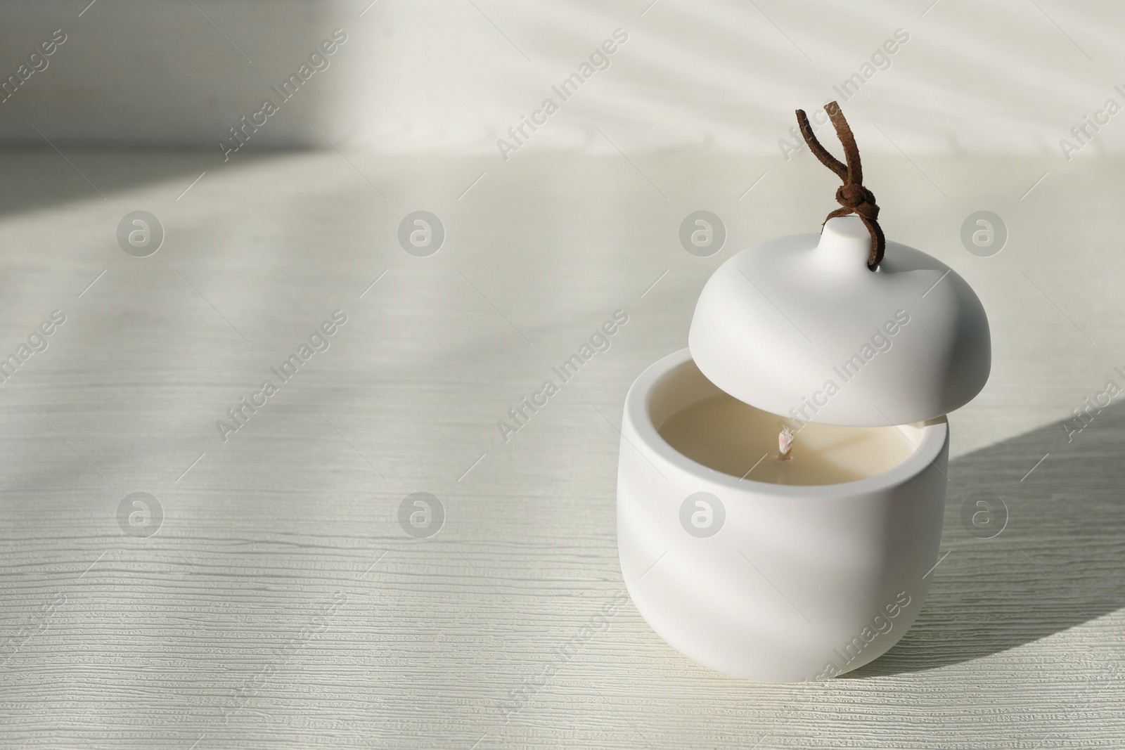 Photo of Soy candle and lid on white wooden table, space for text