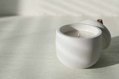 Photo of Soy candle and lid on white wooden table, space for text