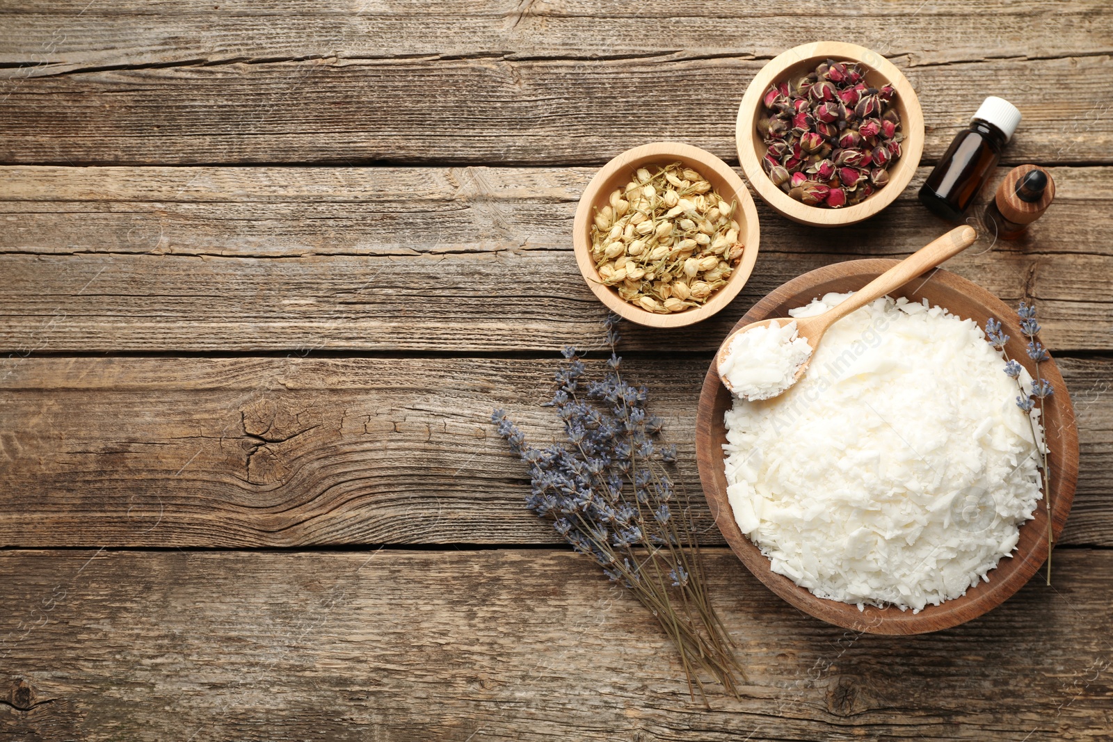 Photo of Soy wax in bowl and other different ingredients for making candles on wooden table, flat lay. Space for text