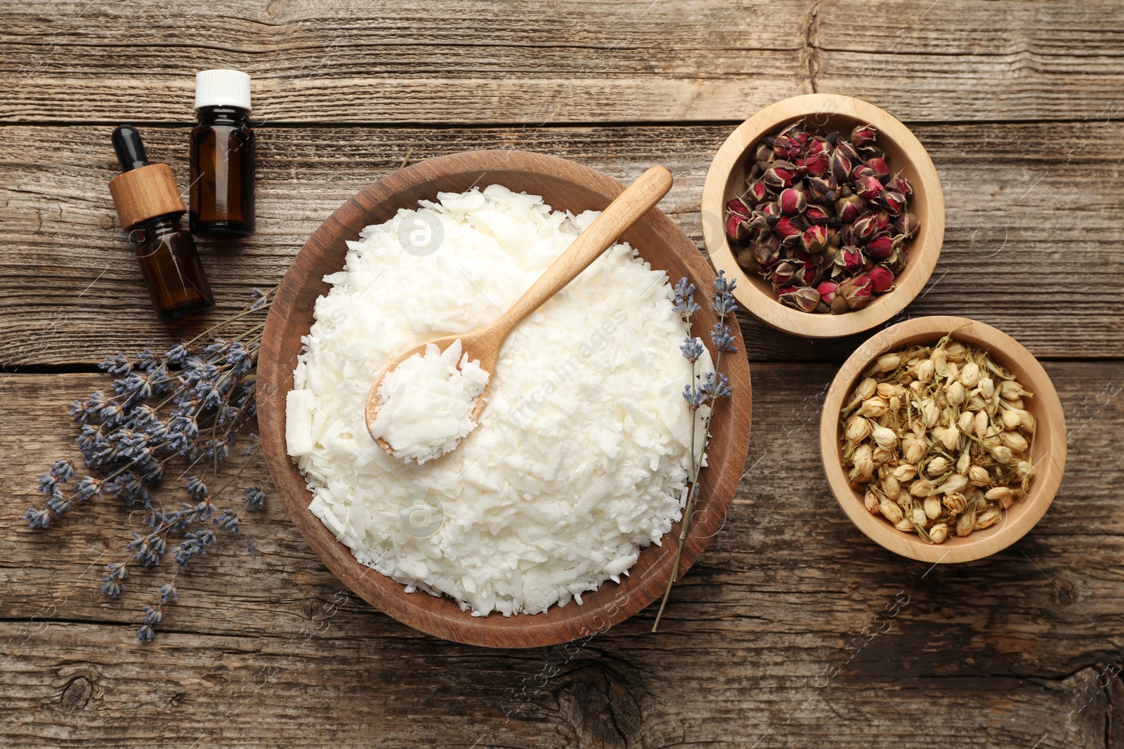 Photo of Soy wax in bowl and other different ingredients for making candles on wooden table, flat lay