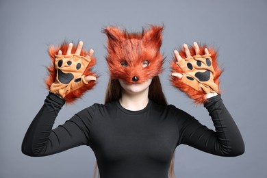 Quadrobics. Girl wearing fox mask and gloves on grey background