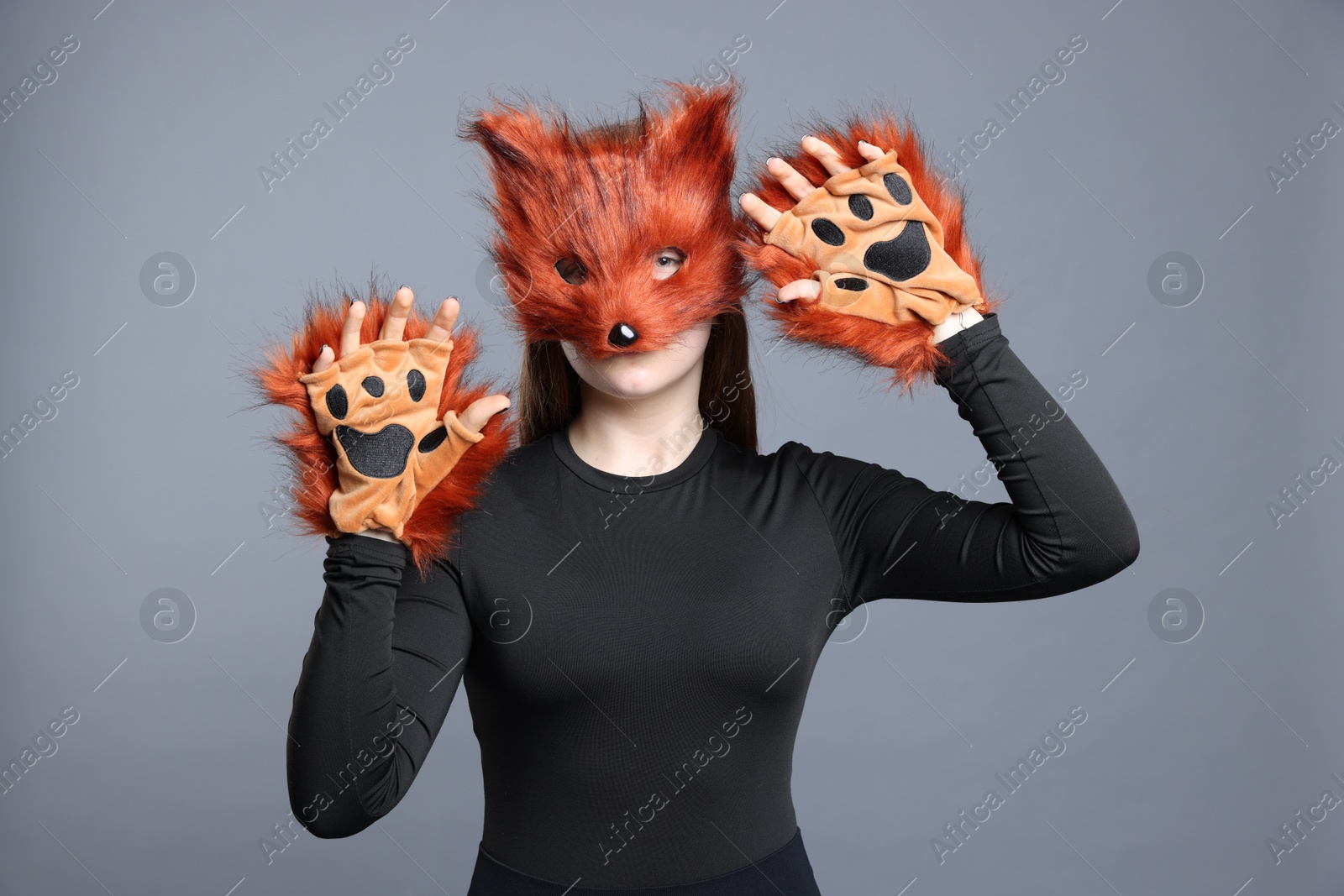 Photo of Quadrobics. Girl wearing fox mask and gloves on grey background