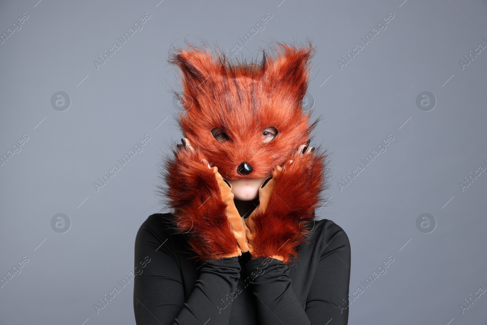 Photo of Quadrobics. Girl wearing fox mask and gloves on grey background