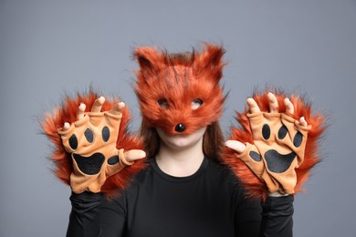 Photo of Quadrobics. Girl wearing fox mask and gloves on grey background