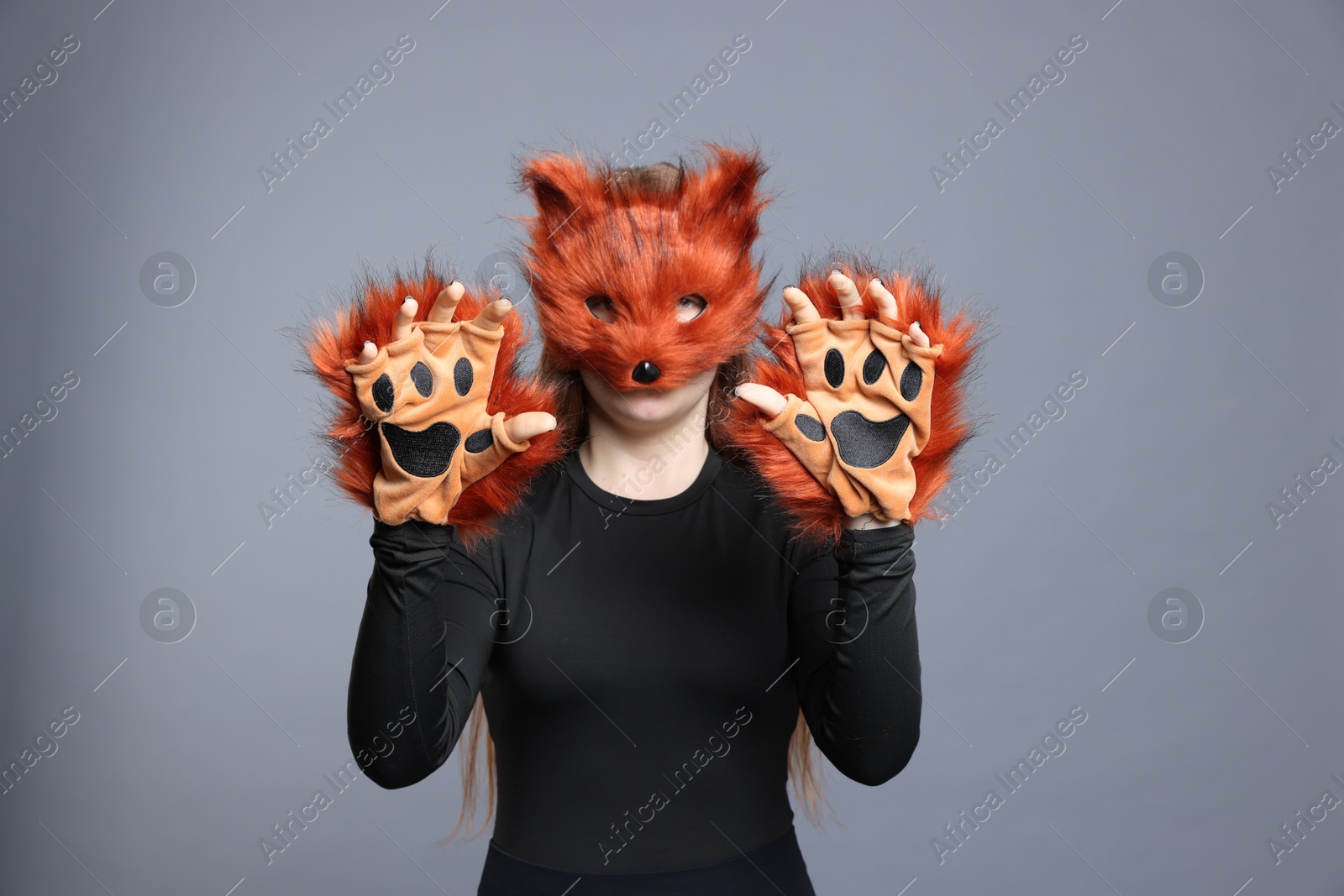 Photo of Quadrobics. Girl wearing fox mask and gloves on grey background