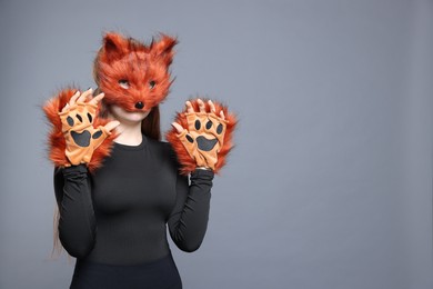 Photo of Quadrobics. Girl wearing fox mask and gloves on grey background, space for text