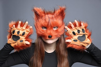 Quadrobics. Girl wearing fox mask and gloves on grey background