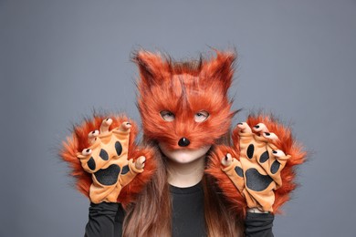 Quadrobics. Girl wearing fox mask and gloves on grey background