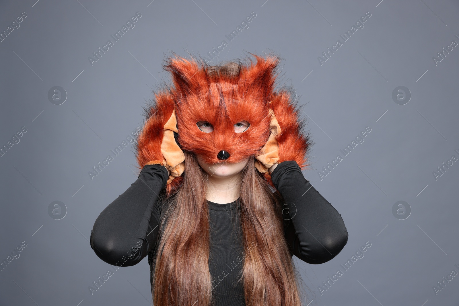 Photo of Quadrobics. Girl wearing fox mask and gloves on grey background