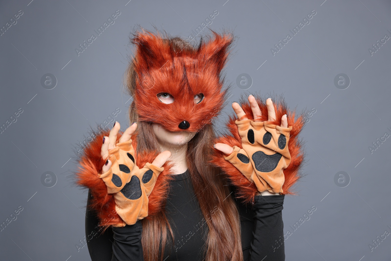 Photo of Quadrobics. Girl wearing fox mask and gloves on grey background