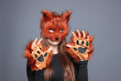 Quadrobics. Girl wearing fox mask and gloves on grey background