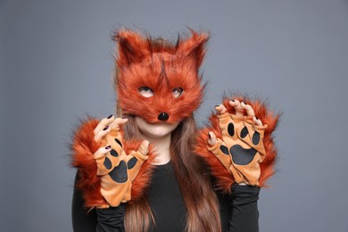 Photo of Quadrobics. Girl wearing fox mask and gloves on grey background