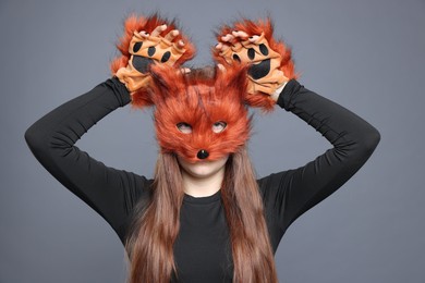 Photo of Quadrobics. Girl wearing fox mask and gloves on grey background