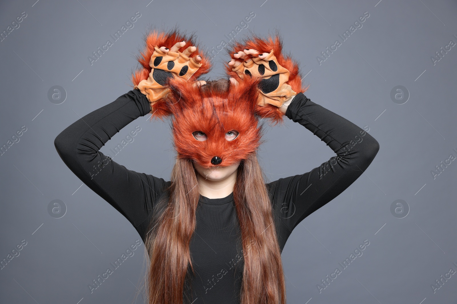 Photo of Quadrobics. Girl wearing fox mask and gloves on grey background