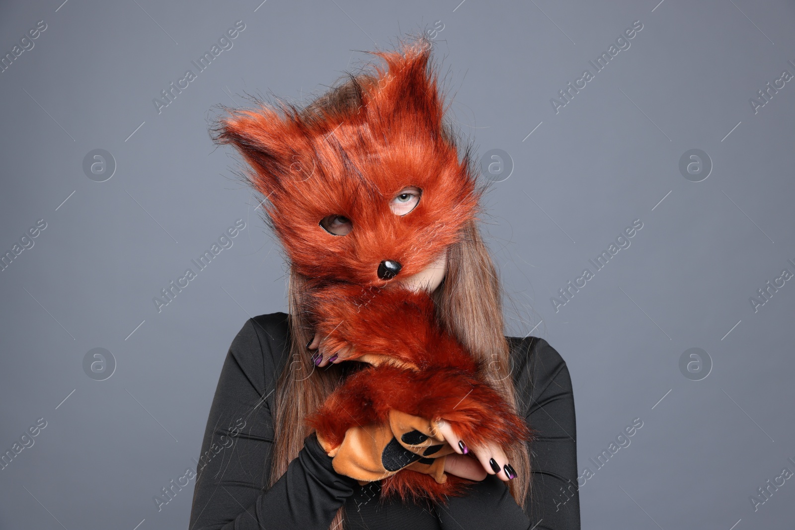 Photo of Quadrobics. Girl wearing fox mask and gloves on grey background